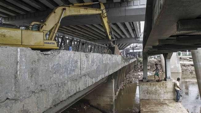 Petugas dibantu alat berat melakukan pembongkaran jembatan permanen yang menghubungkan batas wilayah Cawang-Cililitan di Kalibata, Jakarta, Senin (7/3/2016). [Suara.com/Kurniawan Mas'ud]