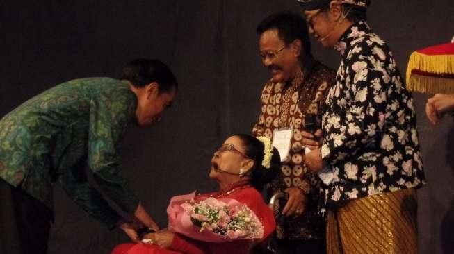 Presiden Joko Widodo memberikan tanda tresno (cinta) kepada penyanyi legendaris keroncong, Waljinah, ‎di Taman Ismail Marzuki, Jakarta, Jumat (1/4/2016) malam. [Suara.com/Erick Tanjung]