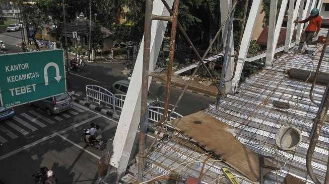 Pekerja menyelesaikan proyek pembangunan Jembatan Penyeberangan Orang (JPO) di Jalan Dr Soepomo, Tebet, Jakarta, Selasa (19/4/2016). [Suara.com/Kurniawan Mas'ud]