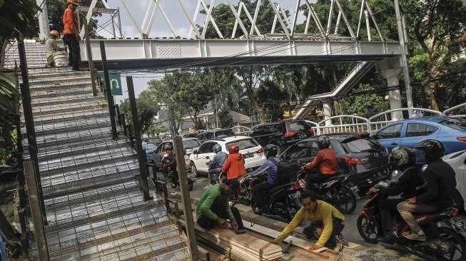 Pekerja menyelesaikan proyek pembangunan Jembatan Penyeberangan Orang (JPO) di Jalan Dr Soepomo, Tebet, Jakarta, Selasa (19/4/2016). [Suara.com/Kurniawan Mas'ud]