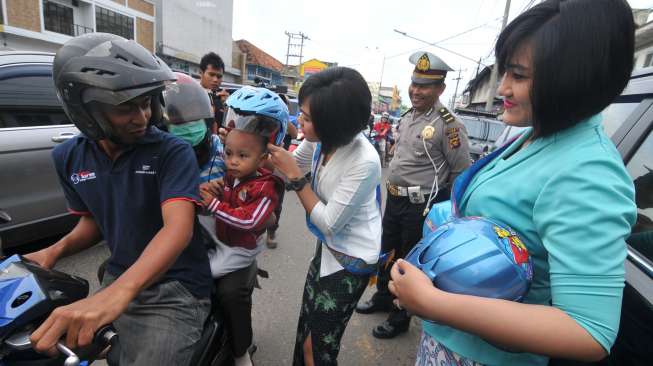 Dua anggota Polwan Polresta Jambi mengenakan kebaya saat membagikan helm ke pengendara sepeda motor di Jalan Hayam Wuruk, Jelutung, Jambi, Kamis (21/4/2016). [Antara/Wahdi Septiawan]