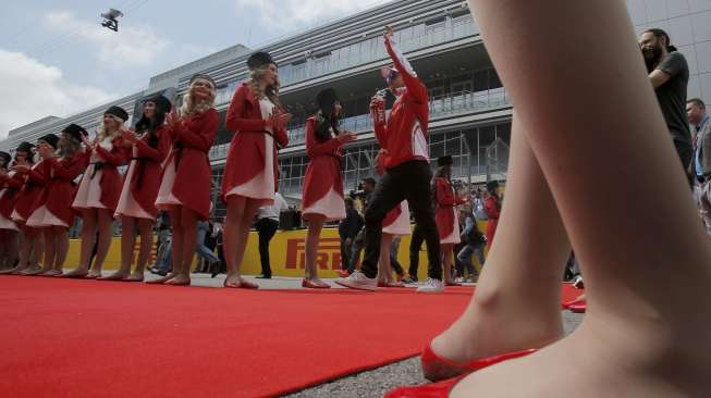 Sebastian Vettel berjalan melintasi karpet merah yang 'dipagari' oleh model-model cantik berpakaian merah-putih, dipadu topi bulu bergaya Cossack warna hitam.[Reuters/Maxim Shemetov]