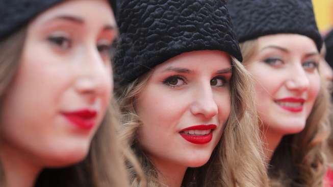 Para driver jet darat berjalan melintasi karpet merah yang 'dipagari' oleh model-model cantik berpakaian merah-putih, dipadu topi bulu bergaya Cossack warna hitam.[Reuters/Maxim Shemetov]