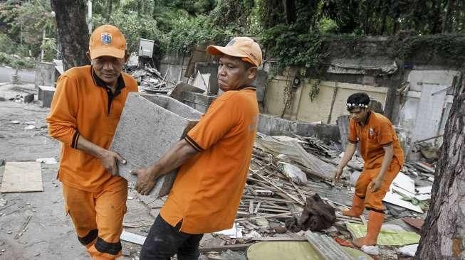 Pekerja Penanganan Sarana dan Prasarana Umum (PPSU) membersihkan lokasi pembongkaran tempat usaha tanaman hias di atas trotoar di kawasan Senayan, Jakarta, Minggu (22/5/2016). [Suara.com/Kurniawan Mas'ud]