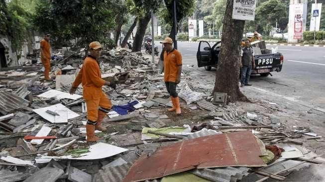 Pekerja Penanganan Sarana dan Prasarana Umum (PPSU) membersihkan lokasi pembongkaran tempat usaha tanaman hias di atas trotoar di kawasan Senayan, Jakarta, Minggu (22/5/2016). [Suara.com/Kurniawan Mas'ud]