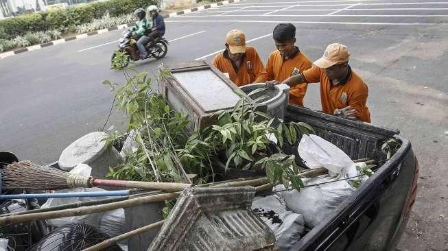 Pekerja Penanganan Sarana dan Prasarana Umum (PPSU) membersihkan lokasi pembongkaran tempat usaha tanaman hias di atas trotoar di kawasan Senayan, Jakarta, Minggu (22/5/2016). [Suara.com/Kurniawan Mas'ud]