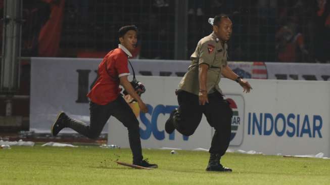 Seorang suporter Persija Jakarta mengejar petugas kepolisian ketika terlibat kericuhan pada laga TSC 2016 di Stadion Utama Gelora Bung Karno, Jakarta, Jumat (24/6/2016) [Antara/Wahyu Putro A]