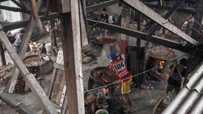 Pekerja memasak adonan dodol di rumah industri olahan dodol Betawi di kawasan Pasar Minggu, Jakarta, Kamis (23/6).[Suara.com/Kurniawan Mas'ud]