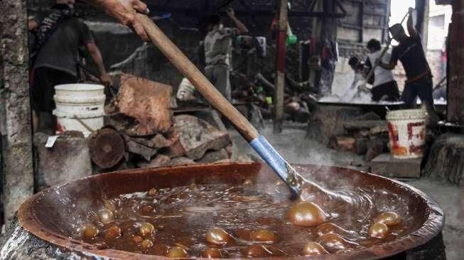 Pekerja memasak adonan dodol di rumah industri olahan dodol Betawi di kawasan Pasar Minggu, Jakarta, Kamis (23/6).[Suara.com/Kurniawan Mas'ud]