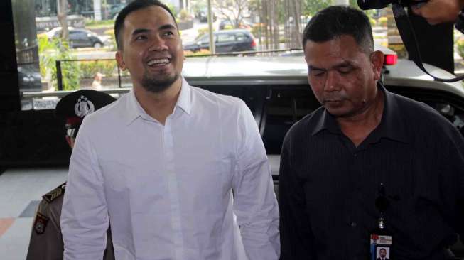 Artis Saipul Jamil melempar senyuman saat turun dari mobil tahanan  untuk diperiksa penyidik KPK, Jakarta, Selasa (19/7). [Suara.com/Oke Atmaja]