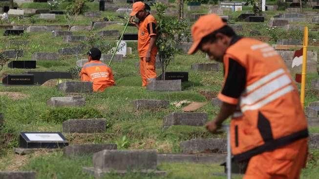 Pekerja Sudin Pertamanan dan Pemakaman Jakarta membuat lubang biopori di TPU Karet Bivak, Tanah Abang, Jakarta Pusat, Jumat (22/7). [Suara.com/Oke Atmaja]