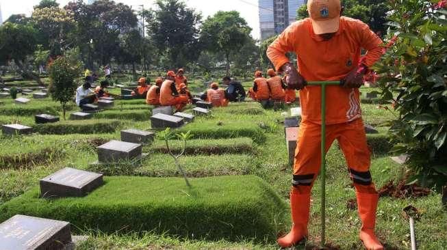 Pekerja Sudin Pertamanan dan Pemakaman Jakarta membuat lubang biopori di TPU Karet Bivak, Tanah Abang, Jakarta Pusat, Jumat (22/7). [Suara.com/Oke Atmaja]