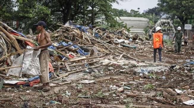 Petugas dibantu alat berat melakukan pembongkaran bangunan semi permanen yang berdiri di lahan milik PT Kereta Api Indonesia (KAI) di Kawasan Gunung Antang, Jatinegara, Jakarta, Senin (25/7/2016). [Suara.com/Kurniawan Mas'ud]