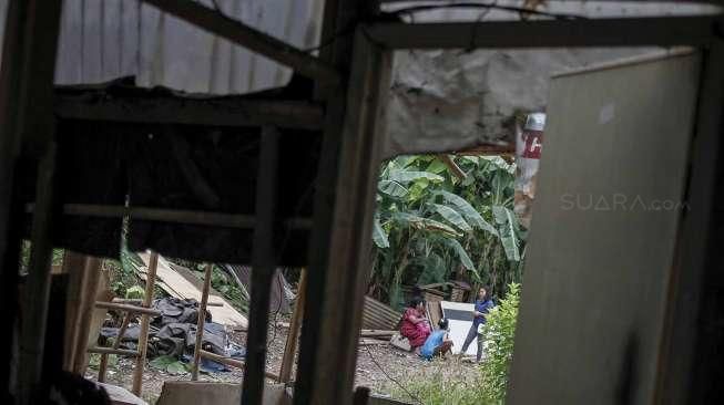 Petugas dibantu alat berat melakukan pembongkaran bangunan semi permanen yang berdiri di lahan milik PT Kereta Api Indonesia (KAI) di Kawasan Gunung Antang, Jatinegara, Jakarta, Senin (25/7/2016). [Suara.com/Kurniawan Mas'ud]