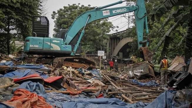 Petugas dibantu alat berat melakukan pembongkaran bangunan semi permanen yang berdiri di lahan milik PT Kereta Api Indonesia (KAI) di Kawasan Gunung Antang, Jatinegara, Jakarta, Senin (25/7/2016). [Suara.com/Kurniawan Mas'ud]