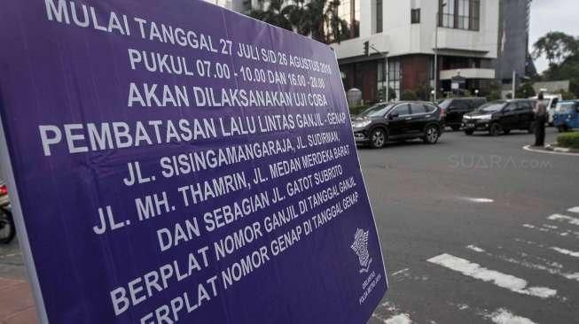 Petugas Polantas dan Dishub melakukan sosialisasi uji coba penerapan sistem pelat ganjil-genap melalui papan informasi, seperti terpampang di Jalan Imam Bonjol, Jakarta, Senin (25/7/2016). [Suara.com/Kurniawan Mas'ud]