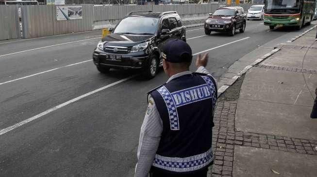 Petugas Polantas dan Dishub melakukan sosialisasi uji coba penerapan sistem pelat ganjil-genap melalui papan informasi, seperti terpampang di Jalan Imam Bonjol, Jakarta, Senin (25/7/2016). [Suara.com/Kurniawan Mas'ud]