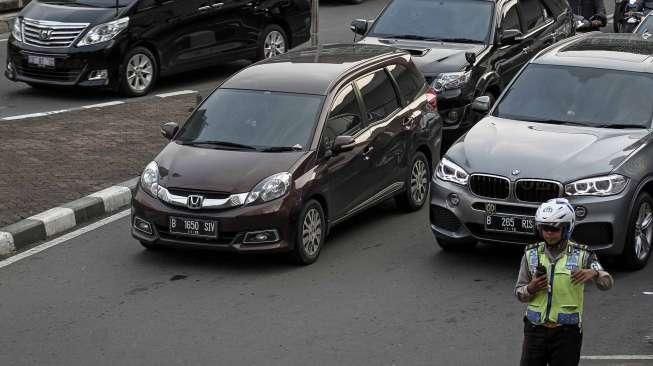 Petugas Polantas dan Dishub melakukan sosialisasi uji coba penerapan sistem pelat ganjil-genap melalui papan informasi, seperti terpampang di Jalan Imam Bonjol, Jakarta, Senin (25/7/2016). [Suara.com/Kurniawan Mas'ud]