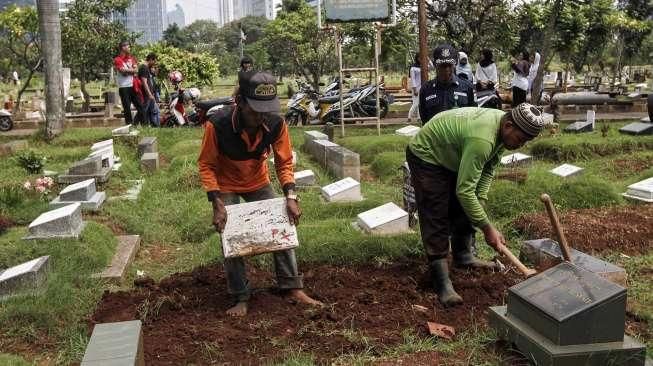 Pekerja membongkar makam fiktif di Tempat Pemakaman Umum (TPU) Menteng Pulo, Jakarta, Kamis (28/7).