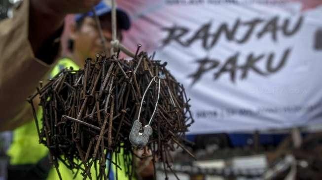 Relawan dari Komunitas Sapu Bersih (Saber) menunjukkan lebih dari 1.000 kilogram paku yang berhasil dikumpulkan dari sejumlah ruas jalan Ibu Kota, di Bundaran HI, Jakarta, Minggu (7/8/2016). [Suara.com/Kurniawan Mas'ud]