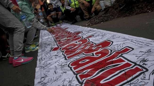Relawan dari Komunitas Sapu Bersih (Saber) menunjukkan lebih dari 1.000 kilogram paku yang berhasil dikumpulkan dari sejumlah ruas jalan Ibu Kota, di Bundaran HI, Jakarta, Minggu (7/8/2016). [Suara.com/Kurniawan Mas'ud]