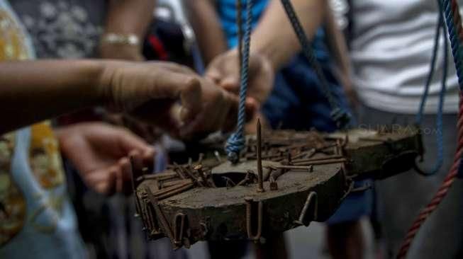 Relawan dari Komunitas Sapu Bersih (Saber) menunjukkan lebih dari 1.000 kilogram paku yang berhasil dikumpulkan dari sejumlah ruas jalan Ibu Kota, di Bundaran HI, Jakarta, Minggu (7/8/2016). [Suara.com/Kurniawan Mas'ud]