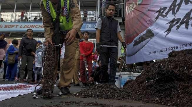 Relawan dari Komunitas Sapu Bersih (Saber) menunjukkan lebih dari 1.000 kilogram paku yang berhasil dikumpulkan dari sejumlah ruas jalan Ibu Kota, di Bundaran HI, Jakarta, Minggu (7/8/2016). [Suara.com/Kurniawan Mas'ud]