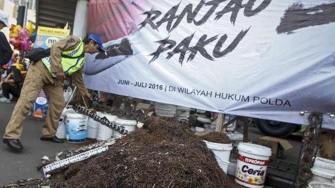 Relawan dari Komunitas Sapu Bersih (Saber) menunjukkan lebih dari 1.000 kilogram paku yang berhasil dikumpulkan dari sejumlah ruas jalan Ibu Kota, di Bundaran HI, Jakarta, Minggu (7/8/2016). [Suara.com/Kurniawan Mas'ud]