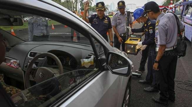 Petugas Dishub DKI Jakarta melakukan pemeriksaan uji KIR khusus kendaraan sewa berbasis transportasi online di kawasan Monas, Jakarta, Senin (15/8/2016). [Suara.com/Kurniawan Mas'ud]