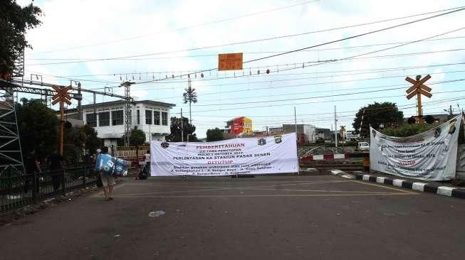 Pejalan kaki melewati pintu perlintasan kereta saat uji coba penutupan pintu perlintasan Kereta Api (KA) di Stasiun Pasar Senen, Jakarta, Sabtu (1/10). [Suara.com/Oke Atmaja]