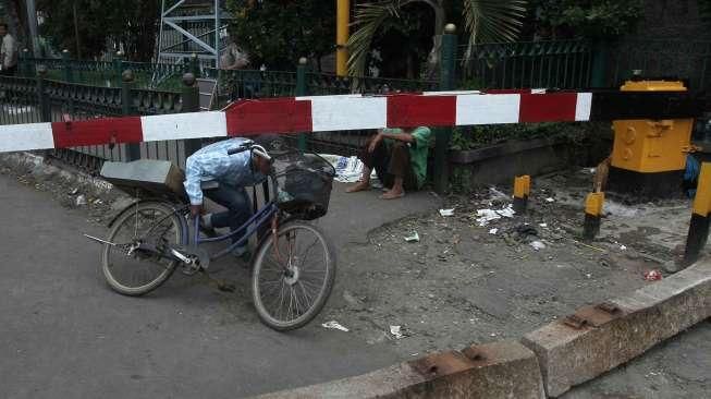 Pejalan kaki melewati pintu perlintasan kereta saat uji coba penutupan pintu perlintasan Kereta Api (KA) di Stasiun Pasar Senen, Jakarta, Sabtu (1/10). [Suara.com/Oke Atmaja]