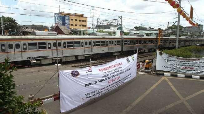 Pejalan kaki melewati pintu perlintasan kereta saat uji coba penutupan pintu perlintasan Kereta Api (KA) di Stasiun Pasar Senen, Jakarta, Sabtu (1/10). [Suara.com/Oke Atmaja]