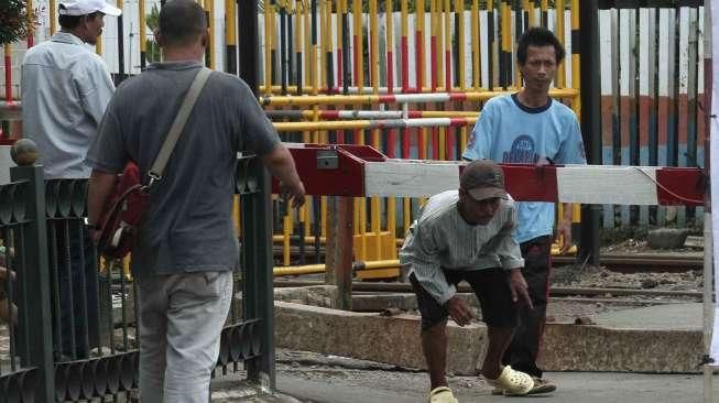 Pejalan kaki melewati pintu perlintasan kereta saat uji coba penutupan pintu perlintasan Kereta Api (KA) di Stasiun Pasar Senen, Jakarta, Sabtu (1/10). [Suara.com/Oke Atmaja]