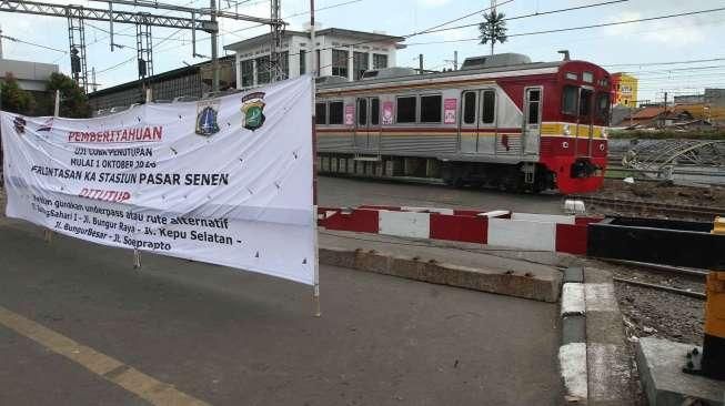 Pejalan kaki melewati pintu perlintasan kereta saat uji coba penutupan pintu perlintasan Kereta Api (KA) di Stasiun Pasar Senen, Jakarta, Sabtu (1/10). [Suara.com/Oke Atmaja]