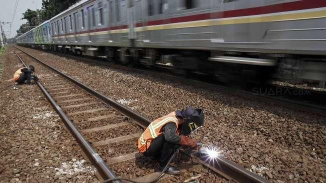 Sejumlah pekerja melakukan perawatan rel kereta api yang menghubungkan Jakarta-Bekasi di jalur Cipinang, Jakarta, Minggu (9/10/2016). [Suara.com/Kurniawan Mas'ud]