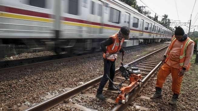 Sejumlah pekerja melakukan perawatan rel kereta api yang menghubungkan Jakarta-Bekasi di jalur Cipinang, Jakarta, Minggu (9/10/2016). [Suara.com/Kurniawan Mas'ud]