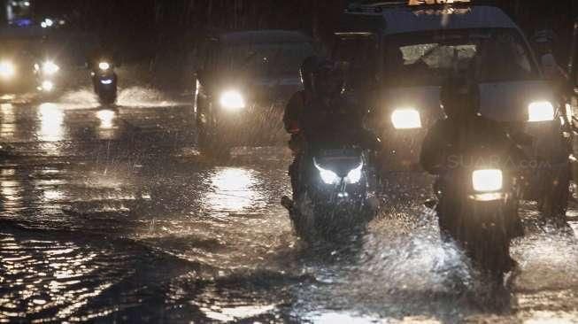 Sejumlah kendaraan tampak melintas di antara genangan banjir di kawasan Kalimalang, Jakarta, Minggu (9/10/2016). [Suara.com/Kurniawan Mas'ud]