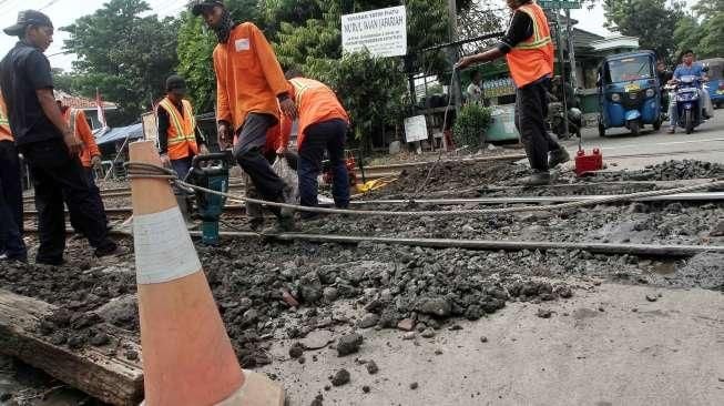 Sejumlah pekerja tampak tengah memperbaiki jalan yang berlubang di perlintasan kereta api kawasan Manggarai, Jakarta, Selasa (11/10/2016). [Suara.com/Oke Atmaja]