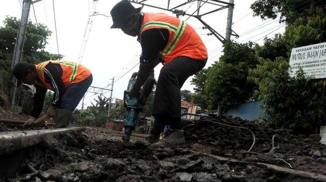 Sejumlah pekerja tampak tengah memperbaiki jalan yang berlubang di perlintasan kereta api kawasan Manggarai, Jakarta, Selasa (11/10/2016). [Suara.com/Oke Atmaja]