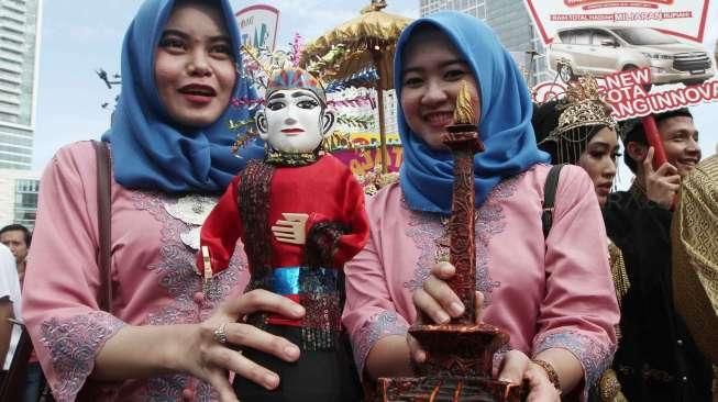 Sejumlah perempuan mengenakan busana penari topeng dalam acara Hajatan Bank DKI saat Car Free Day (CFD) di kawasan Bundaran HI, Jakarta, Minggu (16/10/2016). [Suara.com/Oke Atmaja]