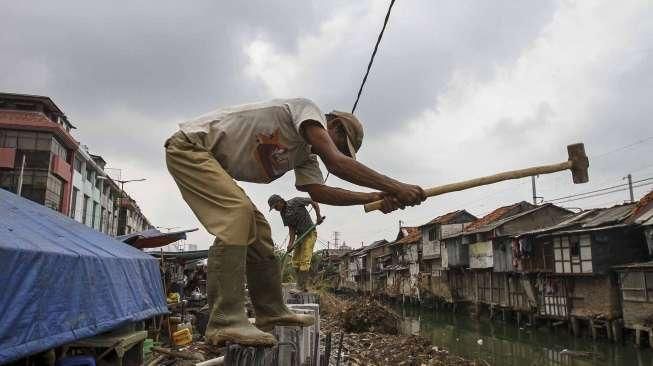 Sejumlah pekerja tampak menyelesaikan proyek pemancangan turap di sepanjang Kali Roxy, Jakarta, Senin (14/11/2016). [Suara.com/Kurniawan Mas'ud]