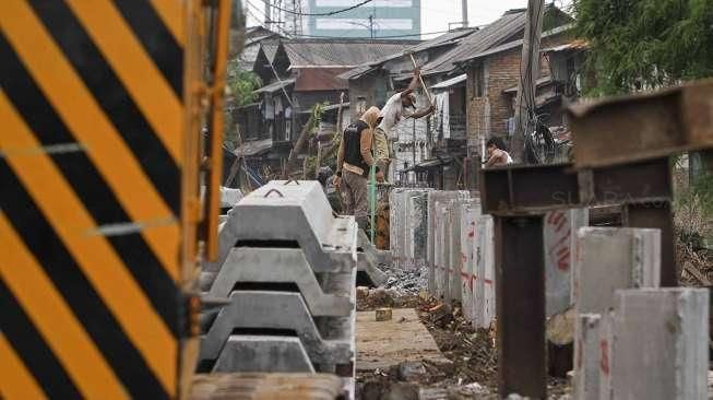 Sejumlah pekerja tampak menyelesaikan proyek pemancangan turap di sepanjang Kali Roxy, Jakarta, Senin (14/11/2016). [Suara.com/Kurniawan Mas'ud]