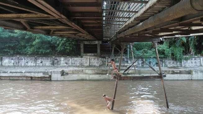 Sejumlah anak tampak asyik bermain air di kawasan Sungai Kenari, Jakarta, Minggu (20/11/2016). [Suara.com/Oke Atmaja]