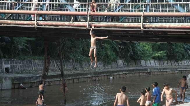 Sejumlah anak tampak asyik bermain air di kawasan Sungai Kenari, Jakarta, Minggu (20/11/2016). [Suara.com/Oke Atmaja]