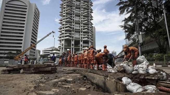 Petugas Dinas Kebersihan bersama Petugas Dinas Tata Air DKI Jakarta membersihkan lumpur yang mengendap di saluran air di Jakarta, Minggu (27/11/2016). [Suara.com/Kurniawan Mas'ud]