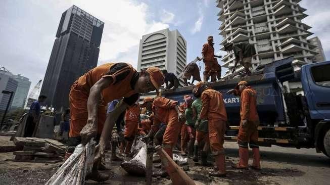 Petugas Dinas Kebersihan bersama Petugas Dinas Tata Air DKI Jakarta membersihkan lumpur yang mengendap di saluran air di Jakarta, Minggu (27/11/2016). [Suara.com/Kurniawan Mas'ud]