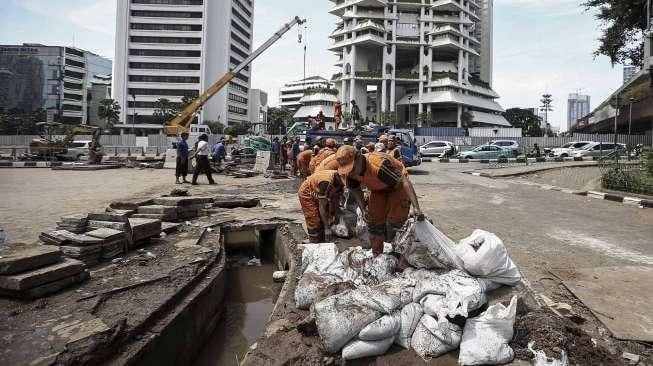 Petugas Dinas Kebersihan bersama Petugas Dinas Tata Air DKI Jakarta membersihkan lumpur yang mengendap di saluran air di Jakarta, Minggu (27/11/2016). [Suara.com/Kurniawan Mas'ud]