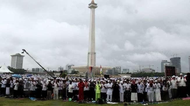 Massa Aksi Damai 2 Desember melakukan salat Jumat berjamaah di bawah guyuran hujan di kawasan Monumen Nasional (Monas), Jakarta, Jumat (12/2/2016). [Suara.com/Oke Atmaja]