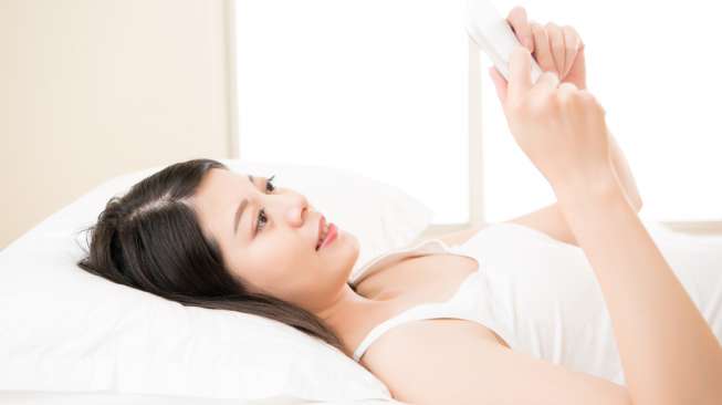 Ilustrasi perempuan membaca sambil tiduran. [Shutterstock]