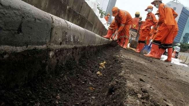 Petugas Pemeliharaan Prasarana dan Sarana Umum (PPSU) membuat jalur air di kawasan Jalan Jenderal Sudirman, Jakarta, Sabtu (3/12/2016). [Suara.com/Oke Atmaja]